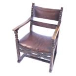 An oak open armchair, with brown leather upholstery on H stretcher.