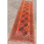 An Afghan runner, with a design of medallions on orange ground with multiple borders, 299cm x 92cm.