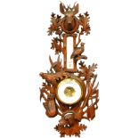 An early 20thC Black Forest barometer and thermometer, heavily carved with stag finial, with partrid