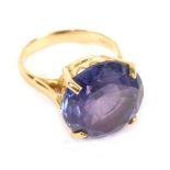 A dress ring, claw set with large amethyst coloured stone, the part pierced shank marked 18ct, size