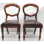 A pair of mahogany balloon back chairs, each with a brown rexine drop in seat, on turned legs.