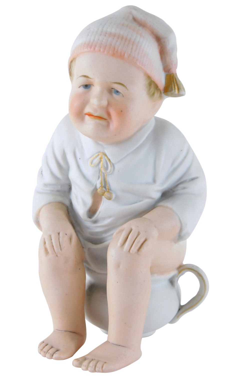 An early 20thC bisque porcelain figure of a child, seated on chamber pot, 19cm high.