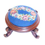 A Victorian mahogany footstool, with later padded wool work top, above a moulded collar and four scr