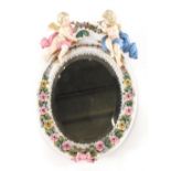 A Dresden style porcelain hanging mirror, of oval form with bevel glass surmounted by two cherubs ho