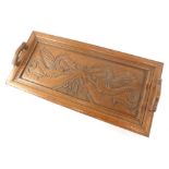 An early 20thC oak tray, of rectangular form with shaped handles heavily carved with dragons, 57cm w