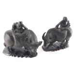 A pair of heavily carved and ebonised Chinese figures on children on buffalo, each on shaped bases,
