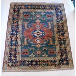 A Persian Kazak style rug, with a design of multicoloured lozenges and medallions on a green ground,