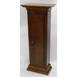 An oak pedestal cabinet, formed from a longcase clock case, on a plinth, 116cm high.