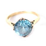 Yellow metal dress ring, claw set with blue zircon.