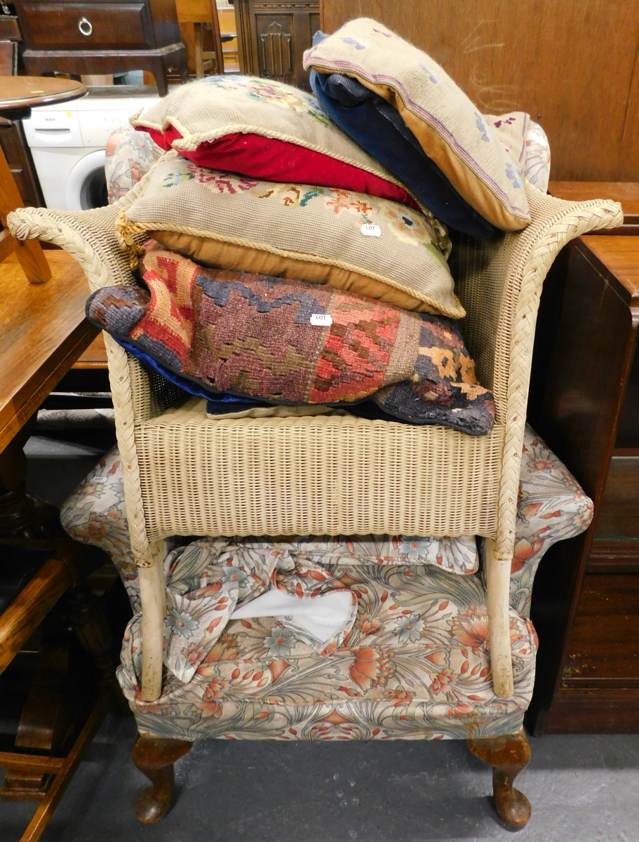 A wingback armchair on cabriole legs, Lloyd Loom chair, and assorted cushions.