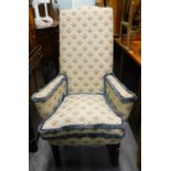 An oak armchair, upholstered in cream and gold fabric with blue piping, on turned legs.