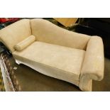 A small chaise lounge in cream material, with inverted ends.