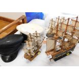 A small wooden model of the HMS Bounty, two others and a peak cap with security badge and another.