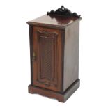 An Edwardian mahogany pot cupboard, with heavily carved cornice raised above a lattice panelled door
