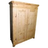 A 20thC pine double wardrobe, the top with a moulded cornice above two panelled doors enclosing a si
