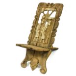 An African carved wood tribal chair, the back carved with two figures and a tree, within a scrolling