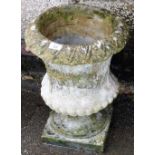 A reconstituted stone urn shaped planter, decorated with leaves and flowers, on a square base, 44cm
