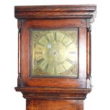 An 18thC country oak long case clock, with plain hood, small arched top trunk door and stepped base,