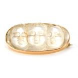 A Victorian moonstone oval bar brooch, depicting three cherubs, in a yellow metal frame, unmarked o