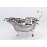 A silver sauce boat, with swing handle, on three acanthus leaf tripod feet, London 2022, bearing ini