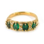 An 18ct gold emerald and diamond gypsy ring, set with four oval cut emeralds, and six tiny diamonds,