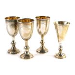 Three George V miniature silver goblets, crested on shaped stems and circular feet, with silver gilt