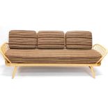 An Ercol beech day bed, with a shaped back and loose cushions to the back and seat on turned taperin