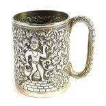 A 20thC Indian mug, heavily repousse decorated with figures and scrolls, with a C scroll handle, and