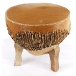 An African animal skin small drum, on three shaped feet, 38cm diameter.