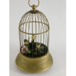 A gilt metal bird cage automaton, containing three birds on a tapering base, cast with scrolls, leav