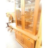 A cherry wood display cabinet, with two glazed doors, the base with three frieze drawers and two pan