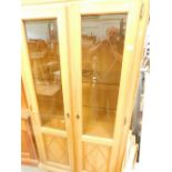 A Continental oak display cabinet, with two glazed and panelled doors enclosing glass shelves, on br