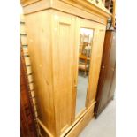 A striped pine wardrobe, with single mirrored door and drawer to the plinth, 108cm wide.