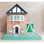 A Tudor style doll's house, twin storey with green and white plastic finish and applied paper brick