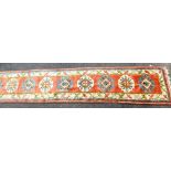 A Turkish wool runner, pink ground with nine medallions within multiple borders, 447cm x 90cm.