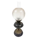 A late 19th/early 20thC oil lamp, with a clear and etched glass shade, brass central reservoir, on a