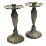 A pair of early 20thC Solkets Tudric hammered pewter candlesticks, with wide drip pan and flared cir