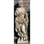 A composition garden statue, of a scantily clad lady, in classical dress holding a bunch of grapes,