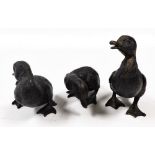 Three bronzed metal figures of ducklings, modelled in various poses, largest 14cm high.