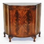A reproduction mahogany and flame mahogany serpentine fronted side cabinet, the top with a carved an