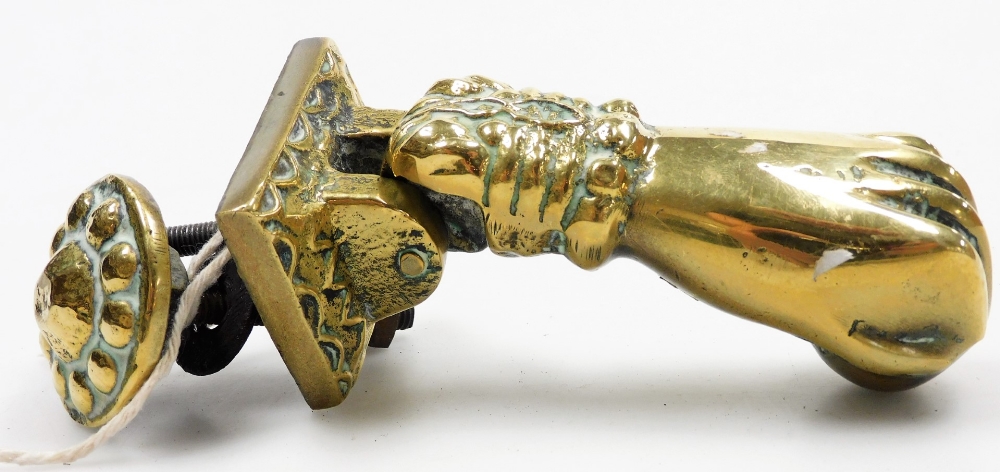 A 19thC brass door knocker, formed as a hand, 13cm long, with brass knocker plate.