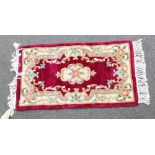 A Chinese wool red ground rug, floral decorated, 117cm x 67cm.