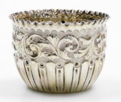 A Victorian silver sugar bowl, with a waved rim, embossed scrolls and part fluted decoration to body