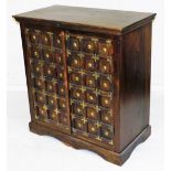 A Chinese hardwood cabinet, the top with a moulded cornice above two multi panelled doors with brass