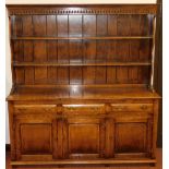A Georgian style oak dresser, the top with a moulded cornice above a plate rack, the base with three