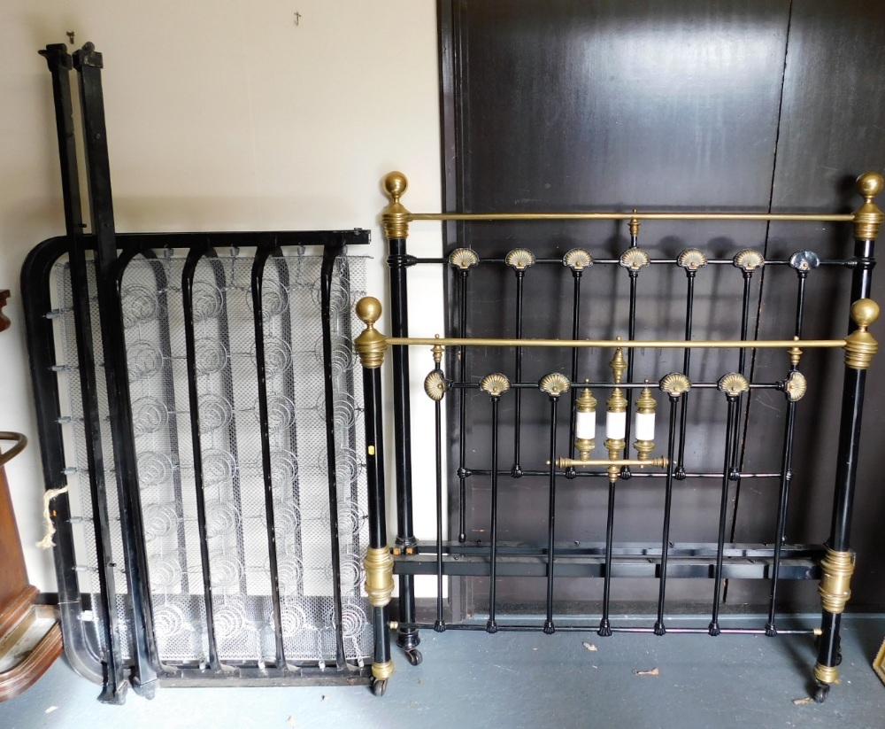 A Victorian brass and cast iron double bed, decorated with shell motifs and with porcelain cylinders