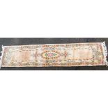 A Chinese pink ground wool runner, floral decorated, 300cm x 70cm.