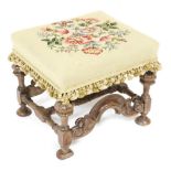A late 19thC Queen Anne style walnut footstool, with a floral wool work top, the base with four carv