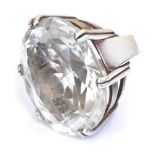 A designer silver dress ring, set with an oval cut crystal, in a high claw mount, size L.