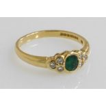 An 18ct gold emerald and diamond ring, the central oval cut emerald surrounded to each side by three